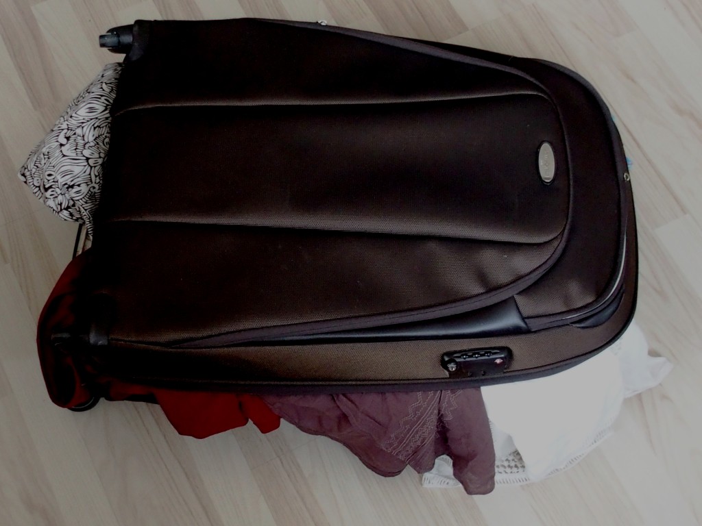 Grande valise brune qui déborde d'habits