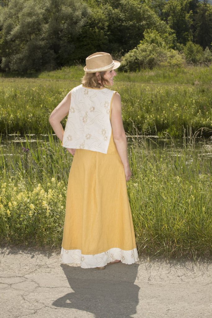 tenue composée d'une jupe longue jaune paille en lin et d'un débardeur en lin brodé écru assorti