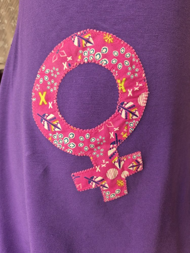 Symbole féminin rose en tissus sur fond violet
